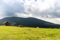 Mountain glade with a house from a log house and sheaves of hay. Royalty Free Stock Photo