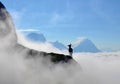 Mountain goat is standing on the top of the hill. High mountains, white clouds below. Royalty Free Stock Photo