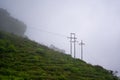 Mountain with high voltage electricity. Transmission tower in meadow and smooth fog. Electrical Power Line and Pylon with Misty Royalty Free Stock Photo