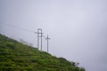 Mountain with high voltage electricity. Transmission tower in meadow and smooth fog. Electrical Power Line and Pylon with Misty Royalty Free Stock Photo