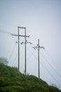 Mountain with high voltage electricity. Transmission tower in meadow and smooth fog. Electrical Power Line and Pylon with Misty Royalty Free Stock Photo