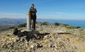 A man with a backpack and walking sticks stands on the summit of the Montgo mountain on the Mediterranean Sea.