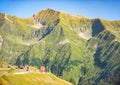 Mountain hut with a red roof on a hill with a beautiful view of high mountain range on background Royalty Free Stock Photo