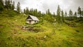 Mountain hut stands near a pine forest covered mountain in the tranquil Julian Alps, Triglav National Park, Slovenia. Royalty Free Stock Photo