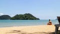 Mountain island over the sea with tourist sit down on the beach on the right side with bright sky in background in the afternoon. Royalty Free Stock Photo