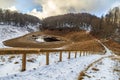 Mountain lake in autumn Caucasus mountain forest. Stairway tourist path leads downward. Beautiful scenic blue sky snow landscape. Royalty Free Stock Photo