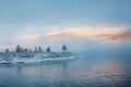 Mountain lake in fog after snowfall in autumn with larch trees Royalty Free Stock Photo
