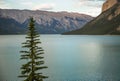 Mountain lake - coniferous forest - pine trees, scenic blue lake, cloudy sky and Rocky Mountains on horizon background. Royalty Free Stock Photo