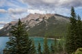 Mountain lake - coniferous forest - pine trees, scenic blue lake, cloudy sky and Rocky Mountains on horizon background. Royalty Free Stock Photo