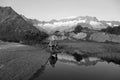 In a mountain lake the landscape is reflected. a hiker makes a break