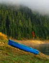 Blue boat near mountain lake during autumn morning with fog Royalty Free Stock Photo