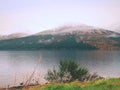 Mountain lake before misty sunset in Higland in Scotland. Snowy cone of mountain above mirroring water