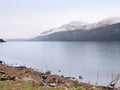 Mountain lake before misty sunset in Higland in Scotland. Snowy cone of mountain above mirroring water