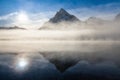 Mountain lake with reflection and fog at sunrise in Jasper National Park, Alberta, Canada The clouds and sun reflect Royalty Free Stock Photo