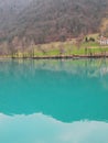 Mountain lake with turquoise blue water, surrounded by alps and green hills.Full peace.The calm water reflects the city on the coa