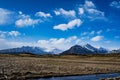 Mountain landscape with bright sky blue, field of gold, glacier and stream Royalty Free Stock Photo