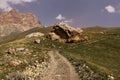 Mountain landscape - country road with big yellow rounded boulder in bright sunny summer day with pink rocky ridge Royalty Free Stock Photo