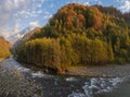 Mountain landscape. Fast river and colorful forest on a sunny day of golden autumn