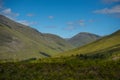 Mountain landscape in the Glencoe area in Scotland, Springtime view mountains with grassland and countryside road in the valley of Royalty Free Stock Photo