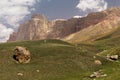 Mountain landscape - high orange steep ridge of canyon in fine sunny summer day with sunbeams, shadow, white clouds in blue sky Royalty Free Stock Photo