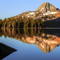 Mountain landscape in morning light with reflection in calm waters of the lake.