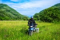 Motorcyclist on motorcycle in a meadow at the foothill of the mountains - mountain landscape - BMW F650 GS