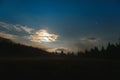 Mountain landscape pine trees near valley and colorful forest on hillside under blue sky with clouds and fog in moon light at Royalty Free Stock Photo