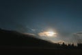 Mountain landscape pine trees near valley and colorful forest on hillside under blue sky with clouds and fog in moon light at Royalty Free Stock Photo