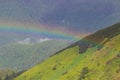 Mountain landscape with a rainbow over flowers Royalty Free Stock Photo