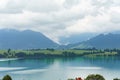 Mountain landscape with serene lake reflecting cloudy sky and lush greenery in the foreground at midday Royalty Free Stock Photo