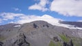 Mountain landscape with snowy peak and rocky foothills. Clip. Stunning view of snowy mountain in clouds on background of