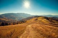 Mountain landscape on a sunny autumn day. View of the mountain slopes and dirt road Royalty Free Stock Photo