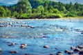 Mountain Landscape on a Sunny Summer Day with a River Splashing and Flowing Over Rocks, Evergreens and Trees on the Banks, a Ridge Royalty Free Stock Photo