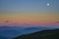 Mountain landscape at sunset. Mountain range at sunset. Moon over the mountain range. Moon in the evening sky over the mountains Royalty Free Stock Photo