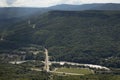 Mountain landscape with valley, river with road and bridge, lash green  ridges with forest of slopes in sunny summer day, panorama Royalty Free Stock Photo