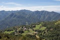 Mountain landscape with village, green slopes, mountains and blue sky on background