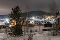Mountain landscape with village in winter, houses and pine trees covered snow at night. Scenery of ski resort with lights. Theme Royalty Free Stock Photo