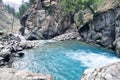 Mountain landscape with a waterfall and a rapid flow of icy blue mountain water Royalty Free Stock Photo