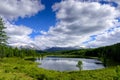 Mountain landscape, white clouds, lake and mountain range in the distance. Fantastic sunny day in mountains, large panorama Royalty Free Stock Photo