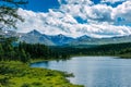 Mountain landscape, white clouds, lake and mountain range in the distance. Fantastic sunny day in mountains, large panorama. Royalty Free Stock Photo