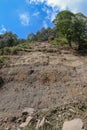 Mountain landslide in an environmentally hazardous area. Large cracks in earth, Descent of large layers of earth blocking road.