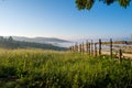 Mountain meadow in a sunrise enclosed by a wooden fence Royalty Free Stock Photo