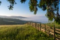 Mountain meadow in a sunrise enclosed by a wooden fence Royalty Free Stock Photo