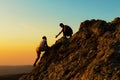 Man Rock Climbing with another Man Helping