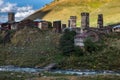 Mountain Murkmeli village in Ushguli community with river under it and bridge and sunny meadows