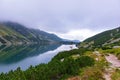 Nature view of mountains with many rocks with blue lake in the middle of mountains with reflection of white clouds