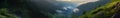 Mountain panorama of the intermountain at dawn with morning fog, bare stone and slopes covered with green coniferous forest of Royalty Free Stock Photo