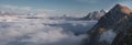 Mountain panorama, snowy peaks above thick clouds against a blue sky Royalty Free Stock Photo