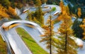 The mountain pass of Maloja, Switzerland. A road with many curves among the forest. Blurred lights of a bus. Landscape in autumn t Royalty Free Stock Photo