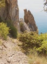 The mountain path goes down to the free-standing narrow rocks protruding from the water Royalty Free Stock Photo